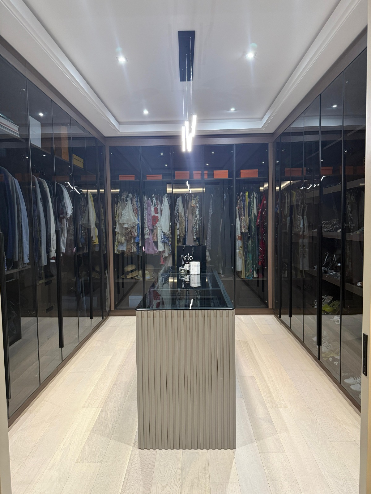 Walk-in wardrobe with smoked glass cabinetry and lit dressing island — Honolulu, O'ahu