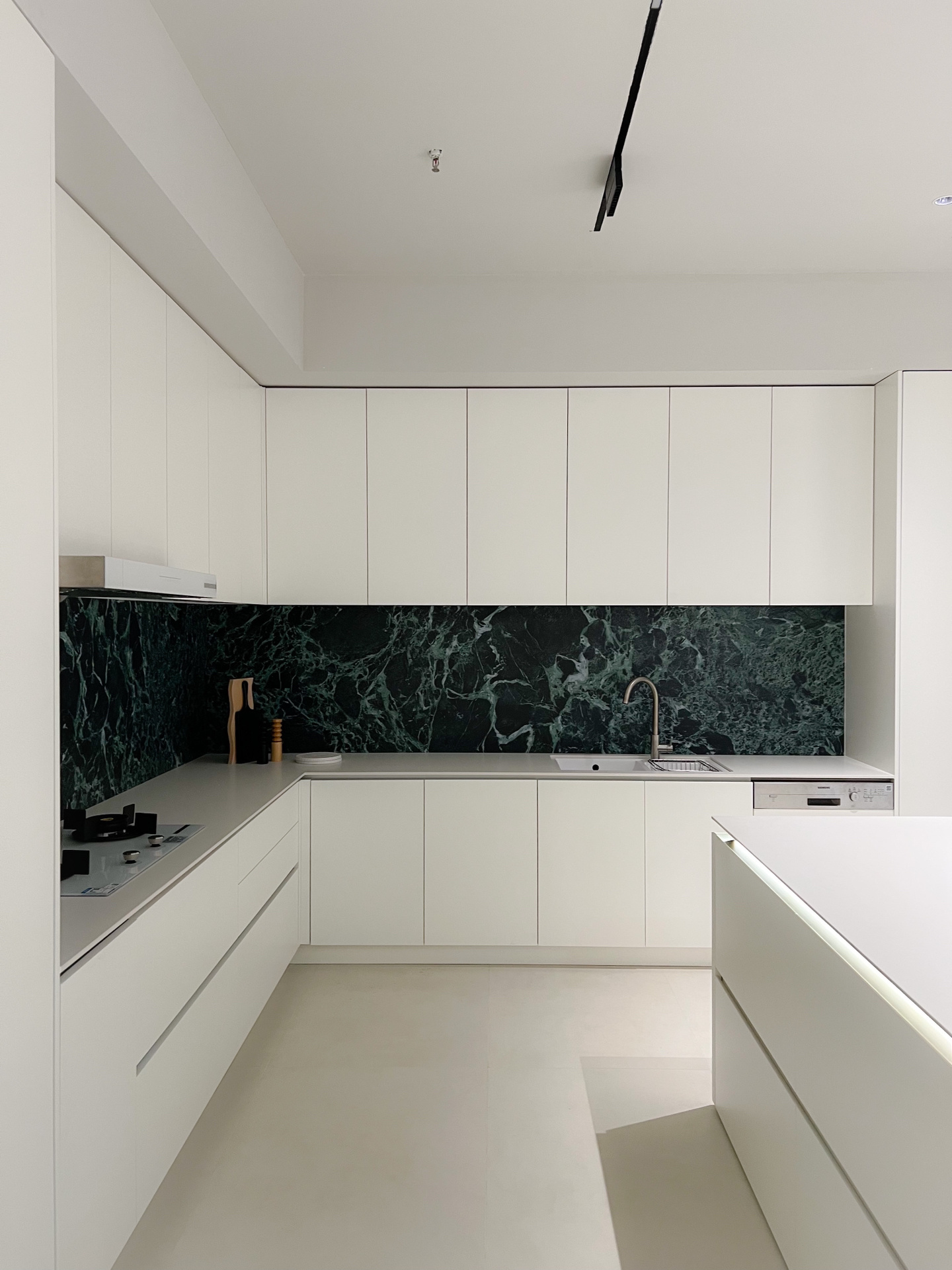 Minimalist white kitchen with green marble backsplash — Kailua, O'ahu