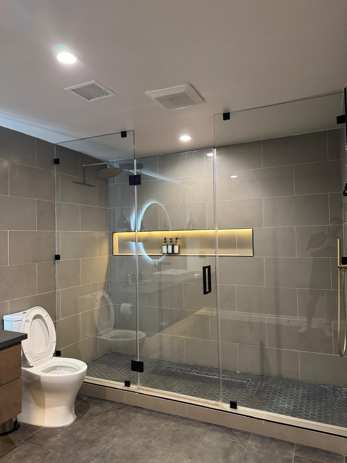 Grey tile bathroom with frameless glass walk-in shower and lit niche — O'ahu