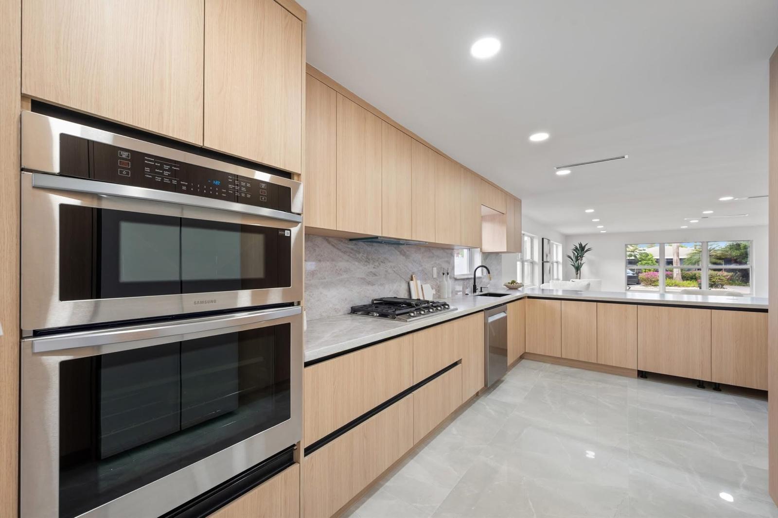 Light oak modern kitchen with double wall ovens and marble backsplash — O'ahu
