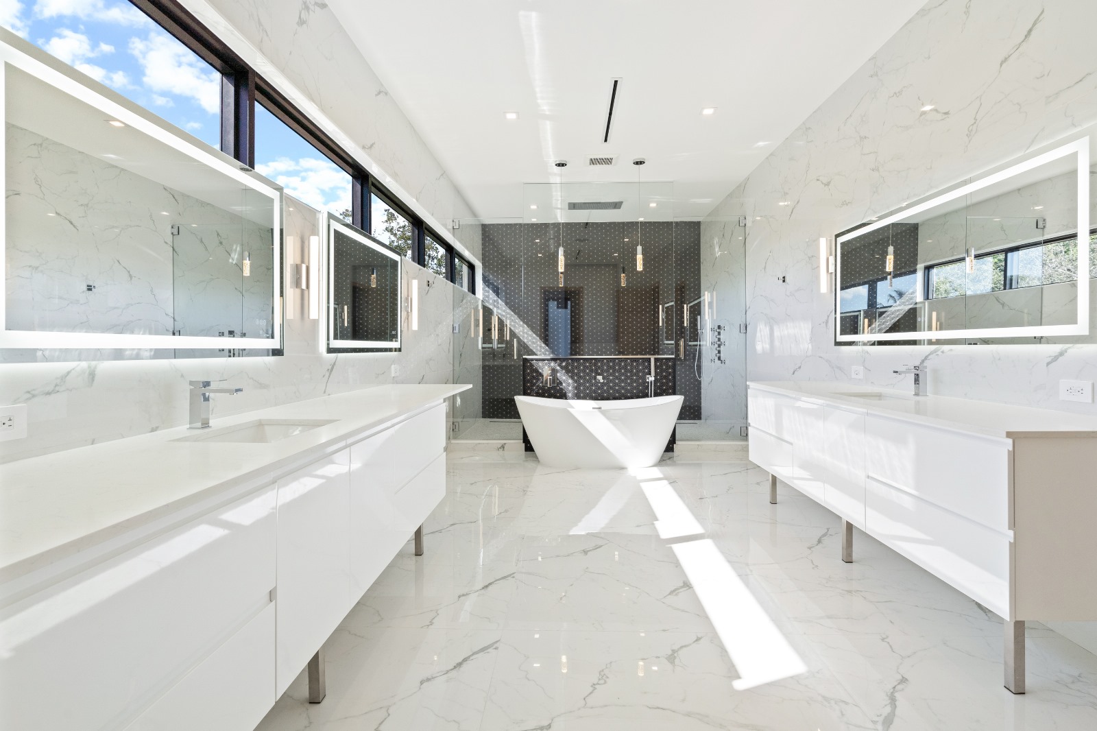 Luxury master bathroom with marble walls, freestanding tub and dual vanities — O'ahu