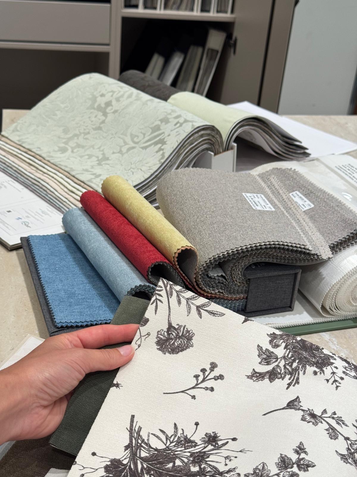 Hand flipping through bound fabric swatch books with damask, linen and floral upholstery samples at Ward Design Center Kapolei design studio