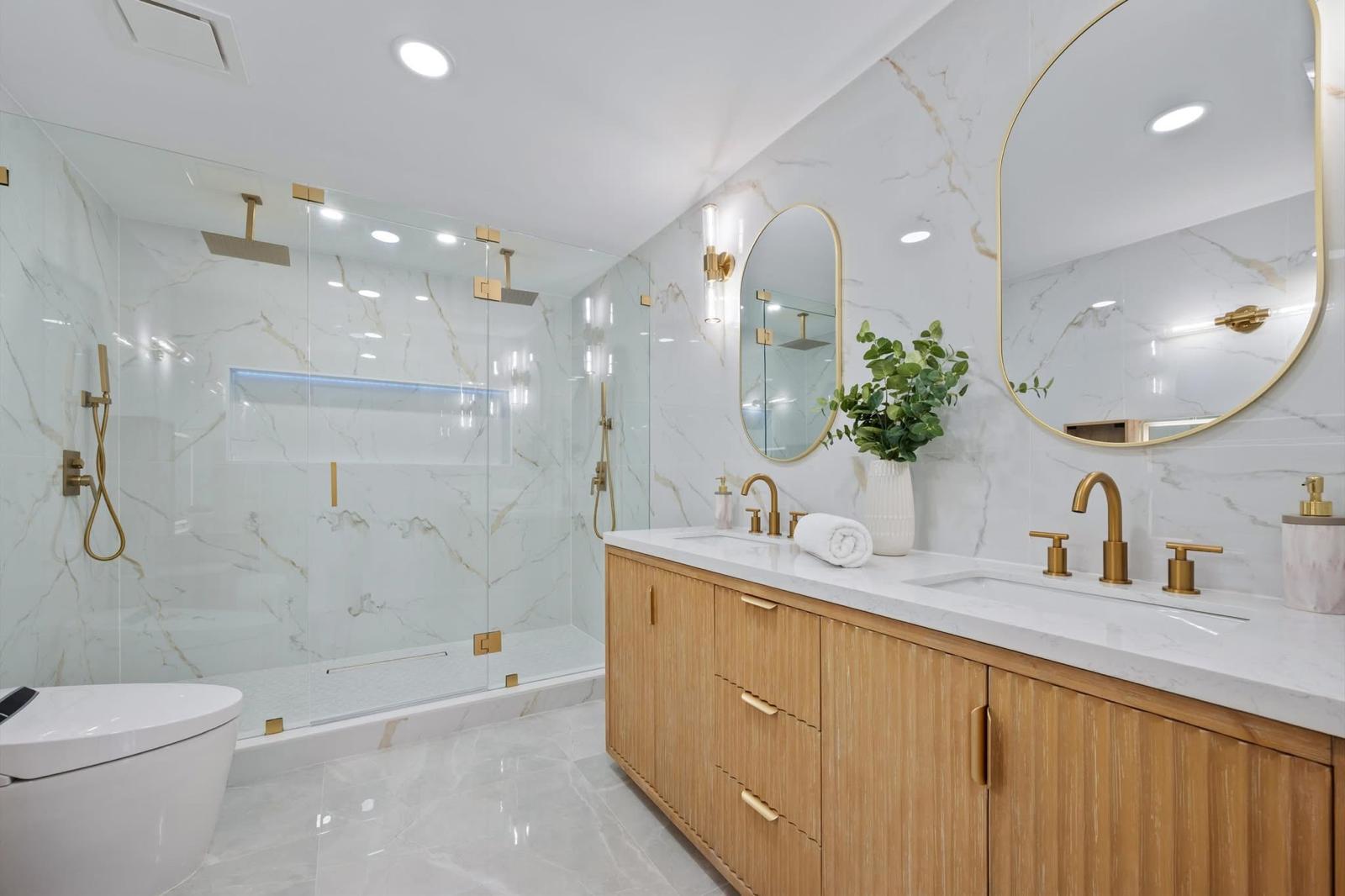 Marble master bath with fluted oak double vanity and brass fixtures — O'ahu