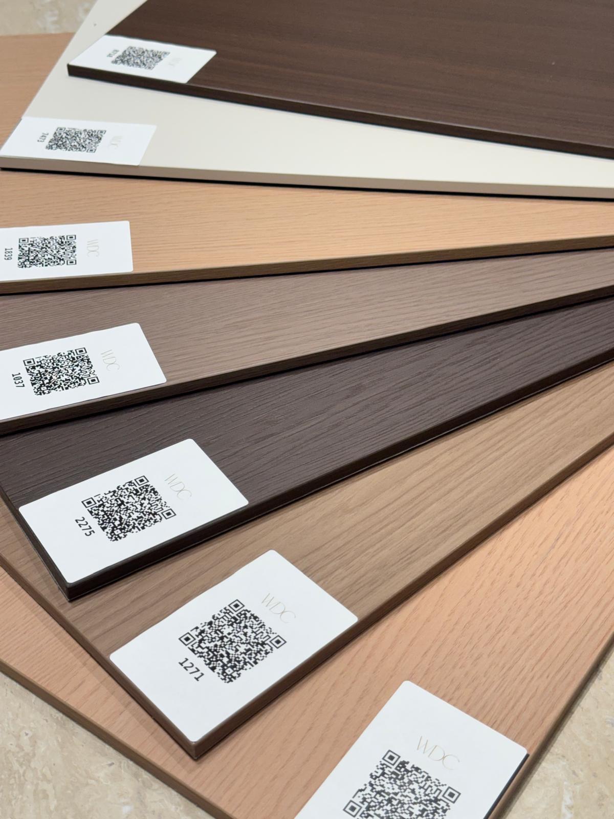 Fan of cabinet door finish samples in walnut, cream, oak and espresso laminate with QR codes at Ward Design Center Kapolei showroom