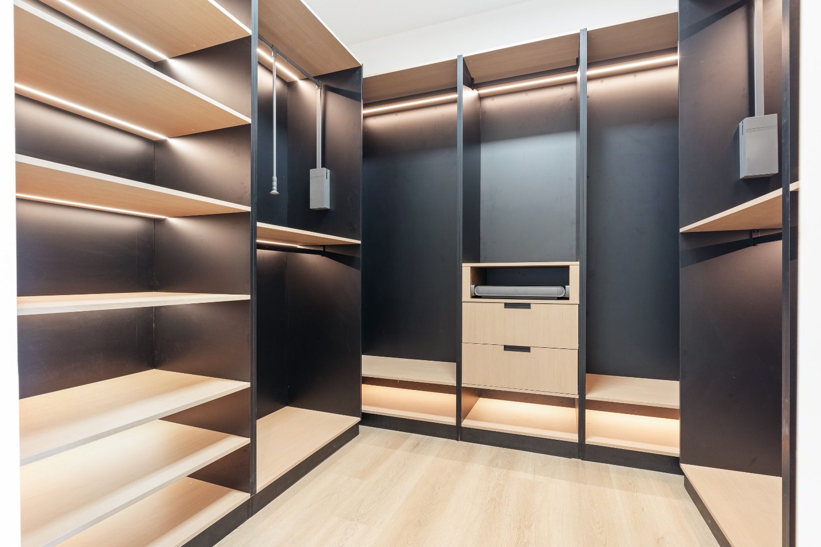 Custom walk-in closet with matte black and oak shelving and LED lighting — O'ahu