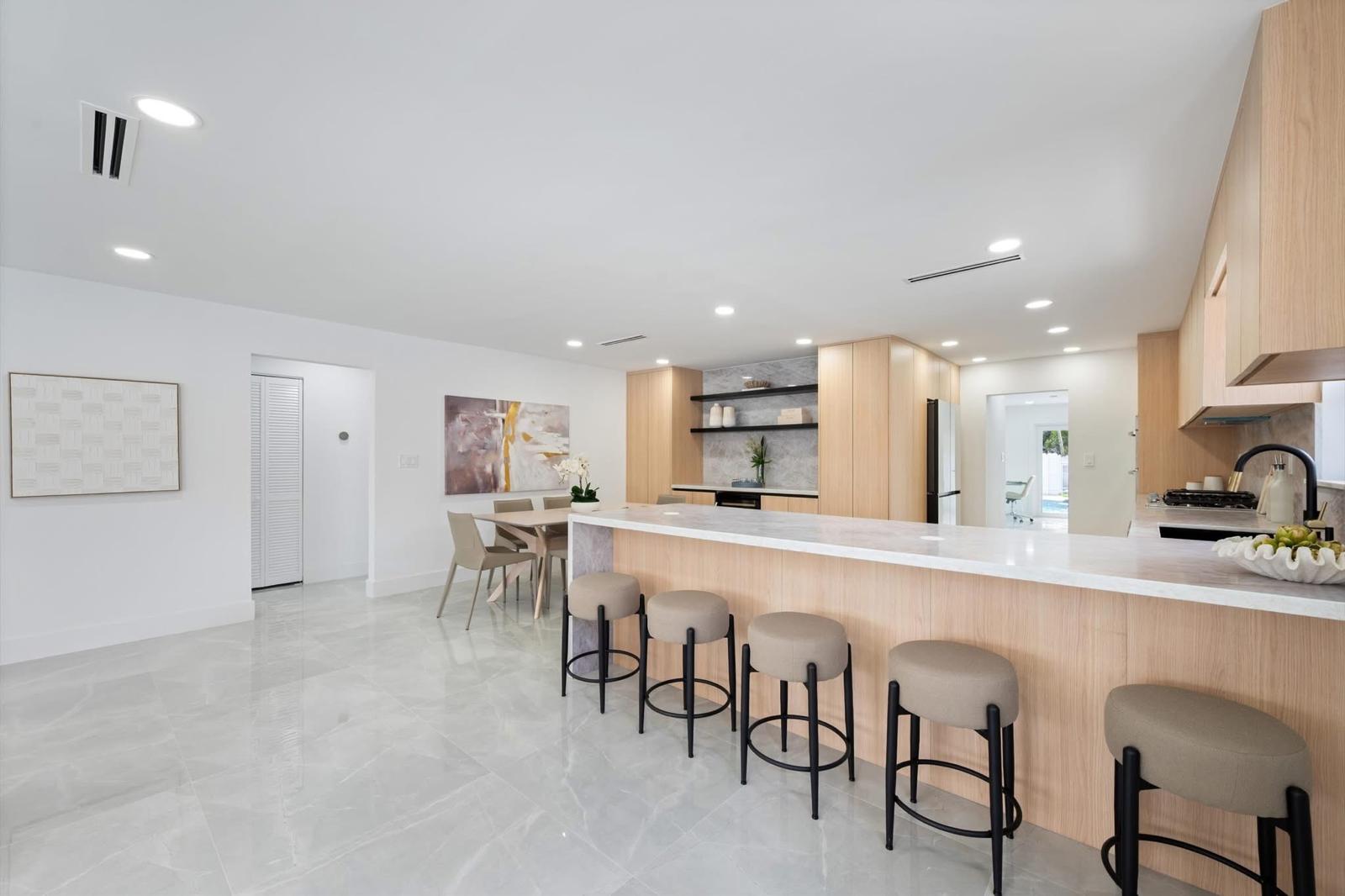Open plan oak kitchen with marble peninsula bar and dining area — O'ahu