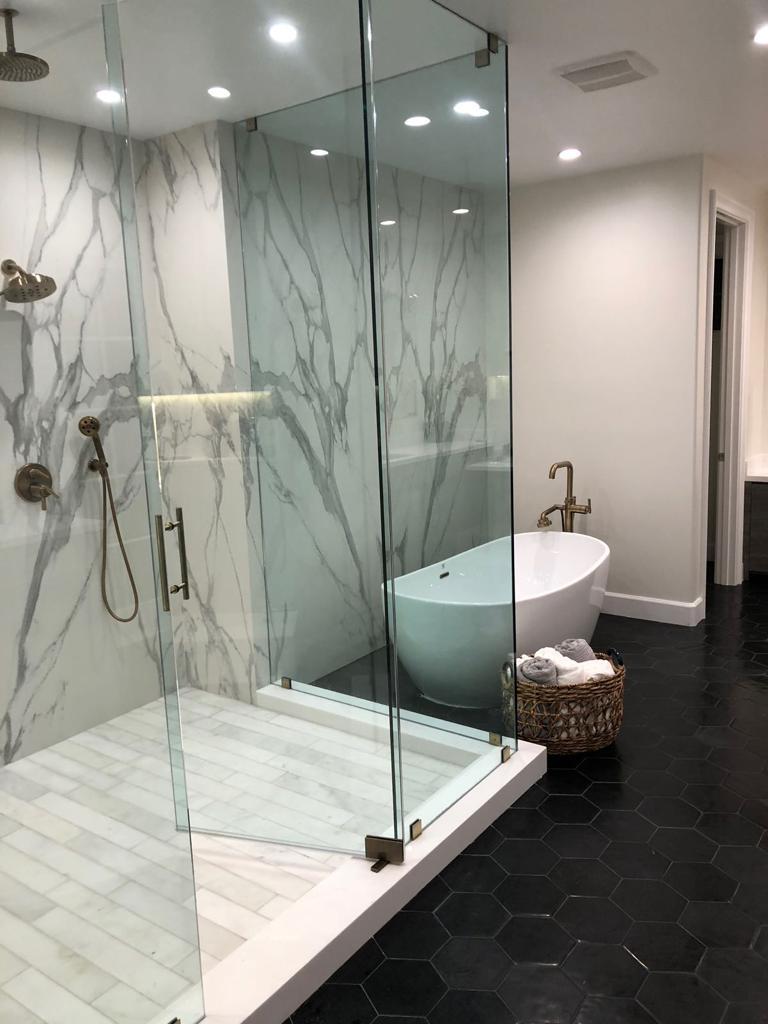 Marble walk-in shower with freestanding tub and black hex tile floor — O'ahu